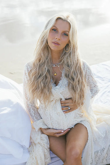 Woman in a white lace outfit sitting on a white surface with a blurred background